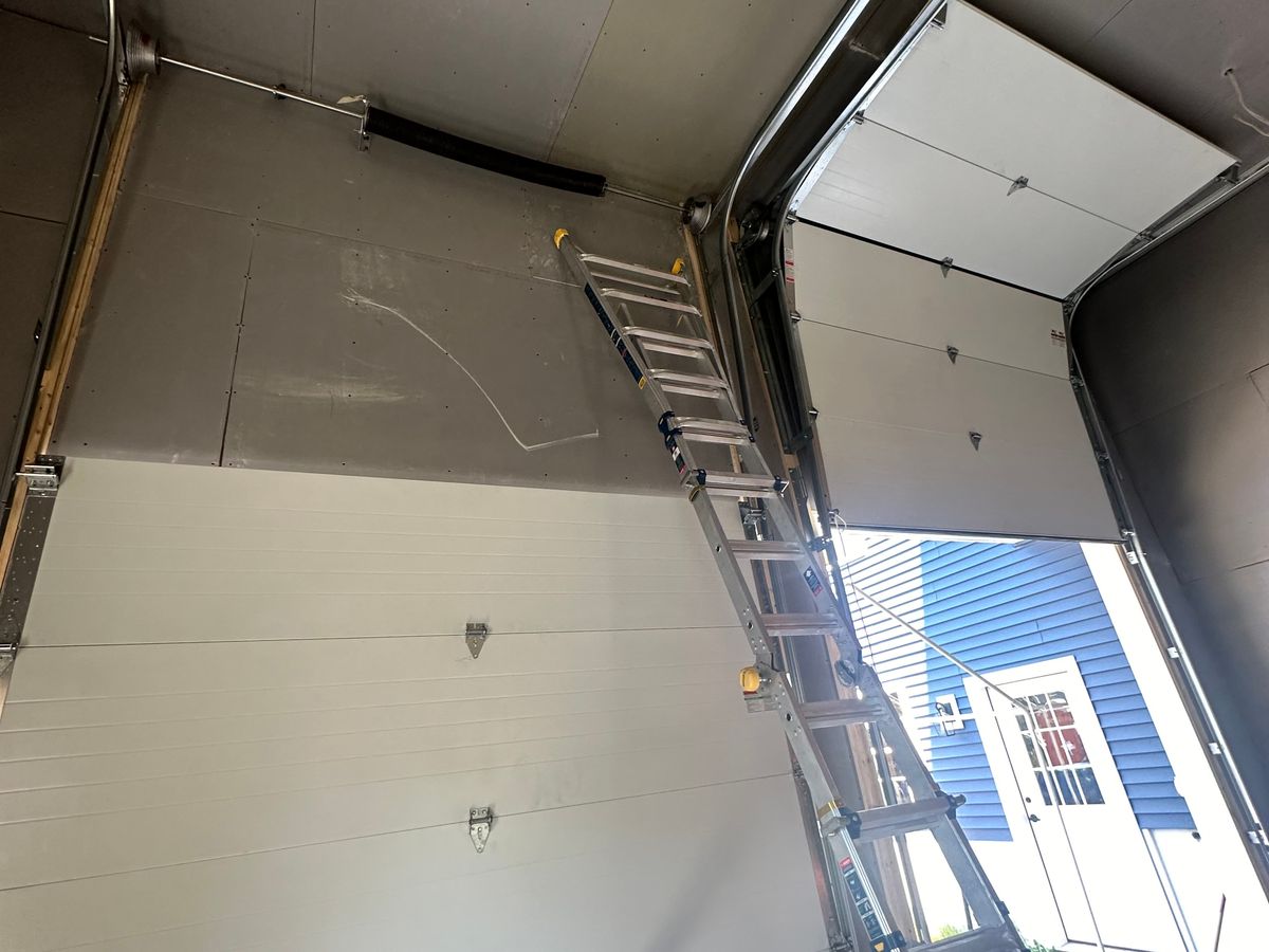 Commercial insulated door installation in progress with ladder and exterior visible