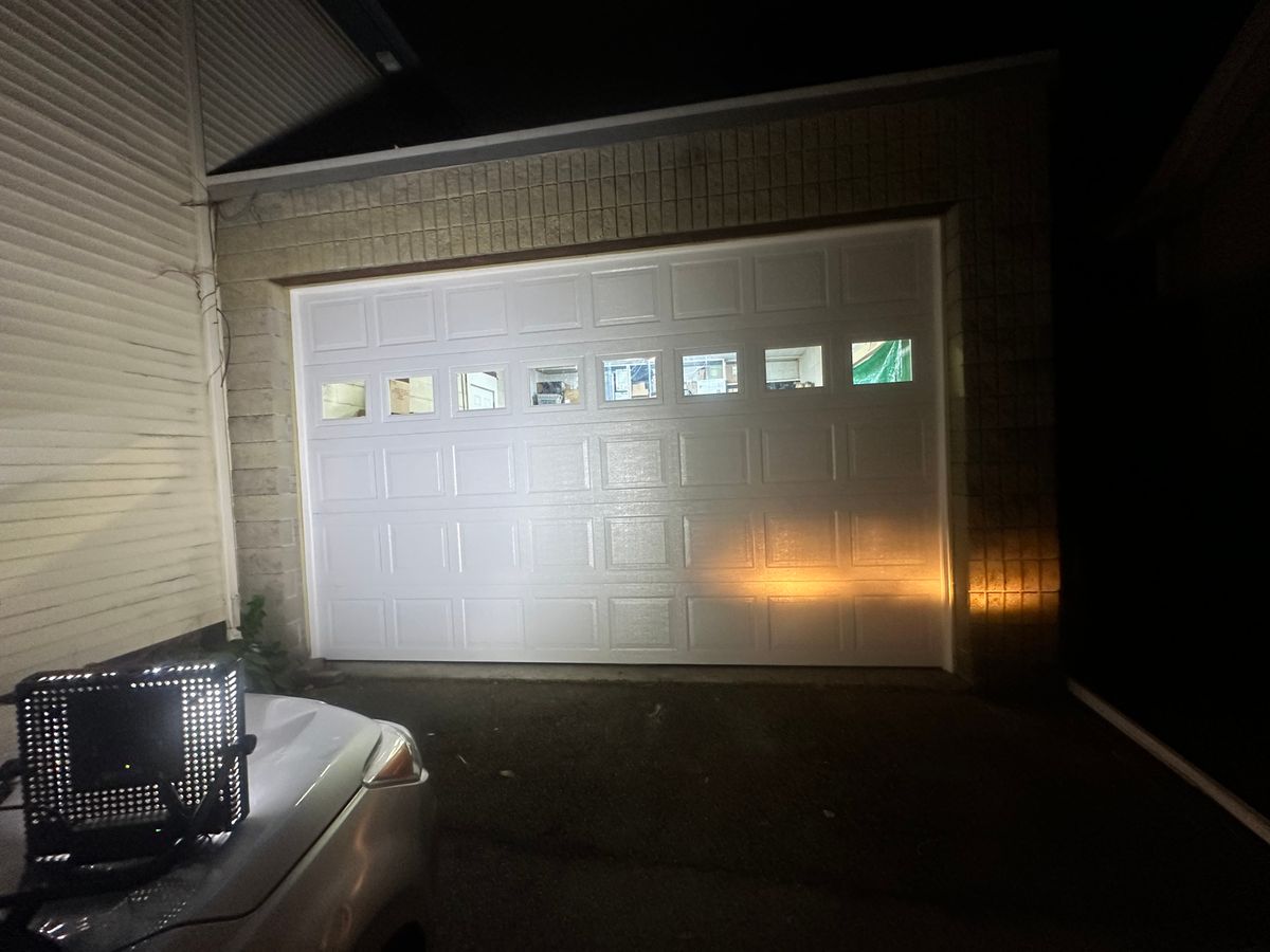 White single raised-panel garage door with windows on dark cedar shingle home